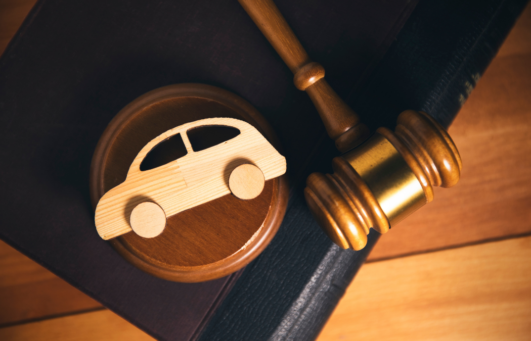 Wooden gavel and toy car model on top of a book, symbolizing legal issues related to automobiles.