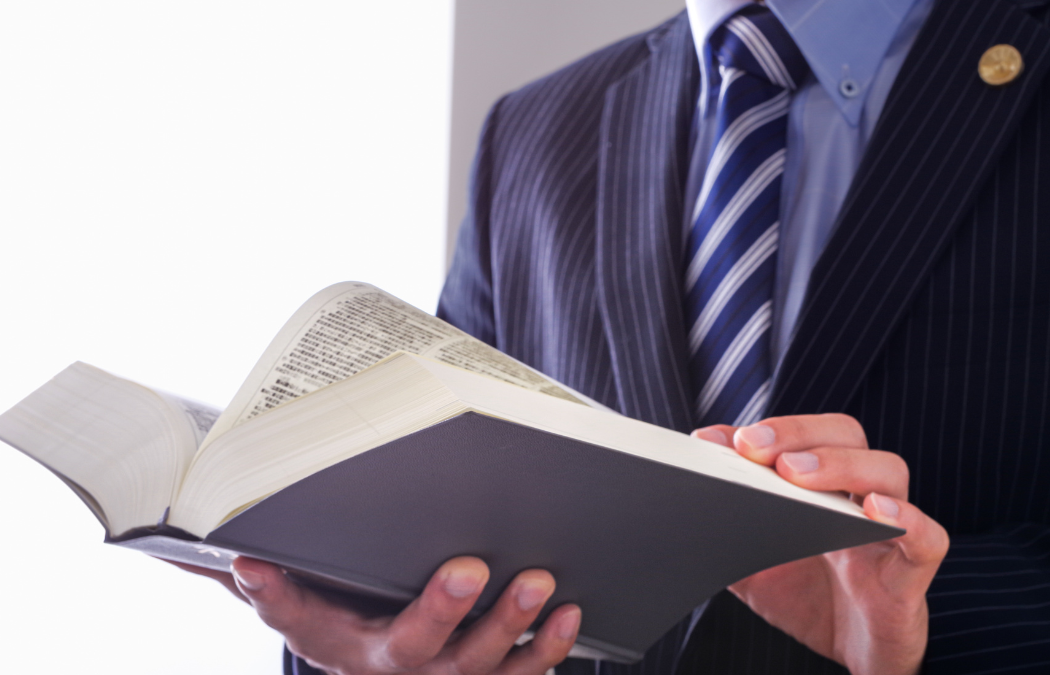 A person in a suit reads an open book, holding it with both hands.